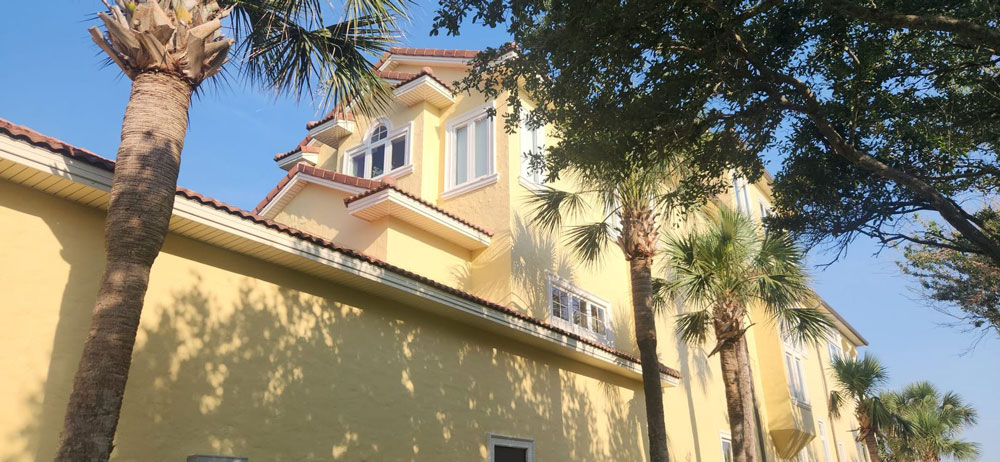 Yellow three-story home beside a lake after exterior painting