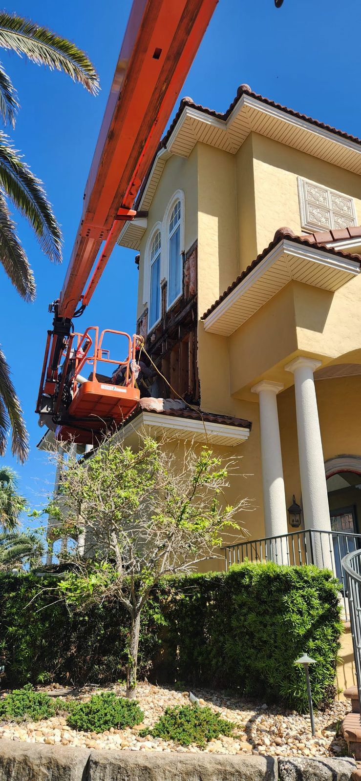 TWG painter on a boom lift repairing rotted wood under a second-floor window