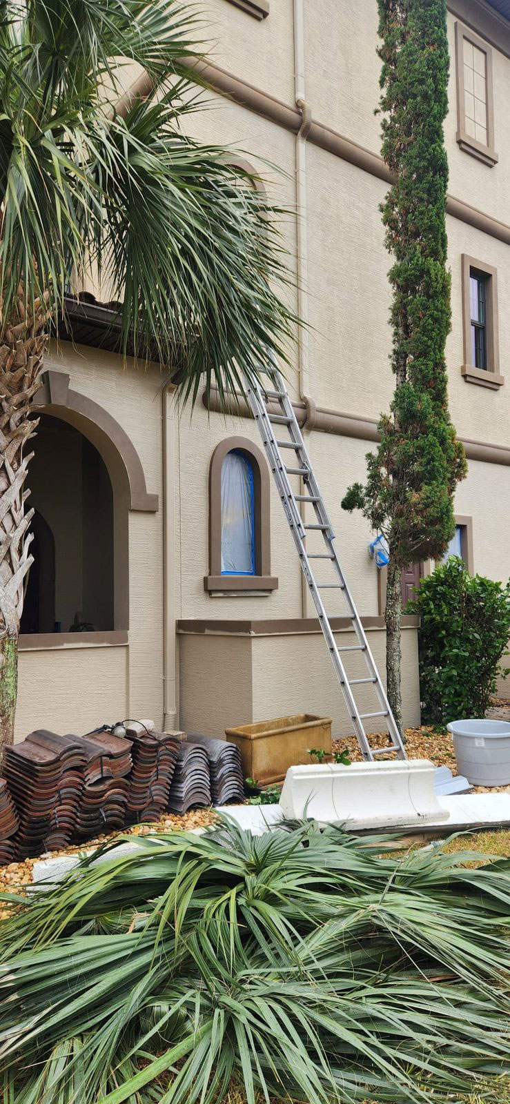 Side of a tan home with windows masked before painting